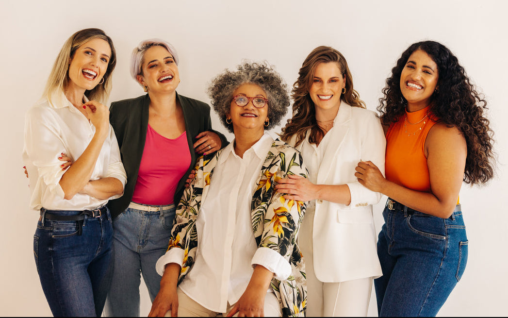 Five women posing together against a plain background