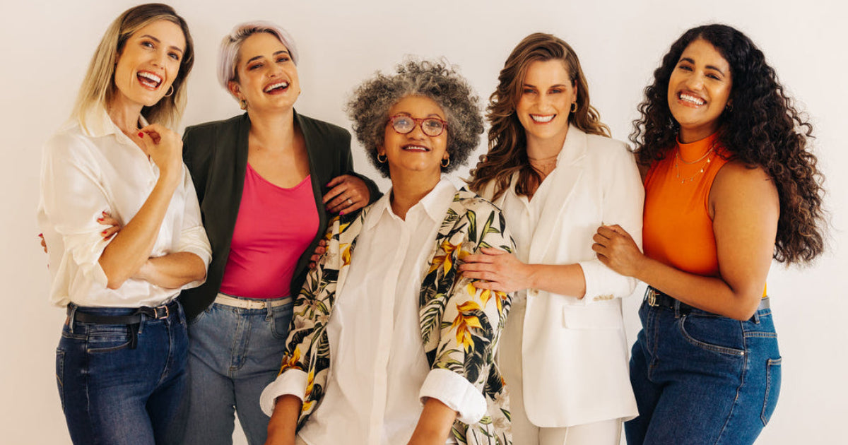 Five women posing together against a plain background